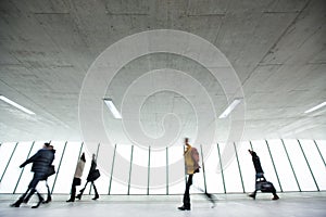 Airport rush: people with their suitcases walking along a corridor (motion blurred image; color toned image)