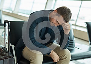 Airport, sad and headache of man waiting to travel, frustrated or depression in transport delay, crisis or problem
