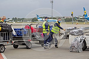 Airport service workers man. Loading suitcases on the plane. Luggage. Trolley with bags. Travel suitcase. Aircraft