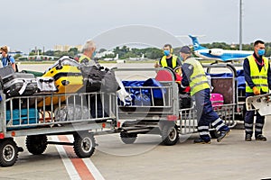 Airport service workers man. Loading suitcases on the plane. Luggage. Trolley with bags. Travel suitcase. Aircraft