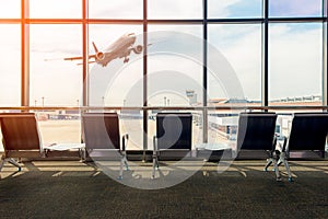 Airport terminal interior with empty seats, background a flying