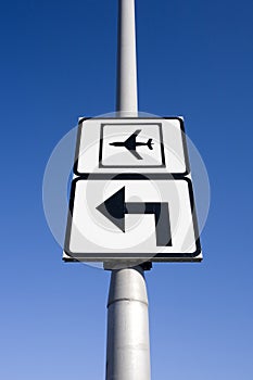 Airport traffic sign with arrow pointing left against blue sky