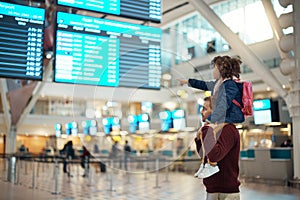 Airport, travel and father with his child on his shoulders reading the schedule or time board. Trip, family and young