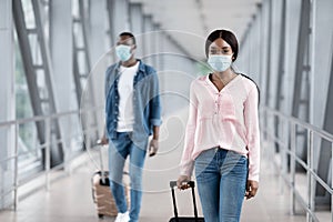 Airport Travel Precautions. Man And Woman Wearing Medical Masks Walking At Terminal photo