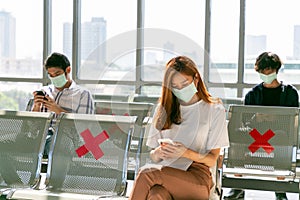 Airport Traveler passenger on smart phone and laptop sitting in terminal hall while waiting for her flight