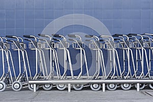 Airport trolley parking lot with empty trolleys and blue wall