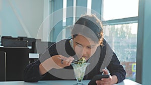 Airport waiting for a flight by plane. Teen girl eats salad and looks smartphone. Internet in a cafe lifestyle