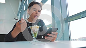 Airport waiting for a flight by plane. Teen girl eats salad and looks smartphone. Internet lifestyle in a cafe. Airport