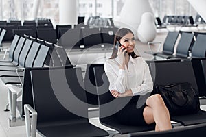 Airport woman on smart phone at gate waiting in terminal. Air travel concept with young casual business woman sitting