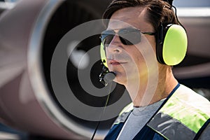 Airport worker in sunglasses and headset at airdrome