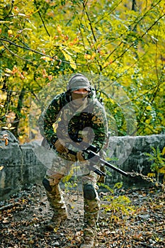 Airsoft man in uniform hold sniper rifle on green forest background photo
