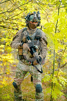Airsoft man in uniform with machine gun standing on yellow forest backdrop. Vertical photo photo