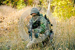 Airsoft man in uniform with sniper rifle, lurking in grass photo