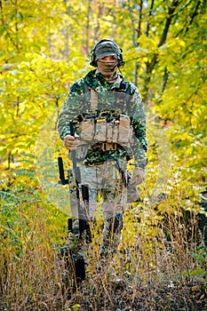 Airsoft, man in uniform stand with sniper rifle on autmn forest background photo