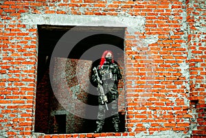 Airsoft red-hair woman in uniform with machine gun standing on ruins photo