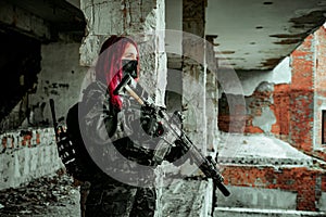 Airsoft red-head woman in uniform and put down machine gun. Soldier standing on balkony. Horizontal photo side view photo