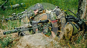 Airsoft sniper men with guns lay on hill. Sniper and aimer on operation