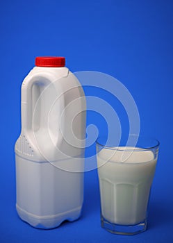 Airtight one gallon milk jug with a red cap and full glass milk.
