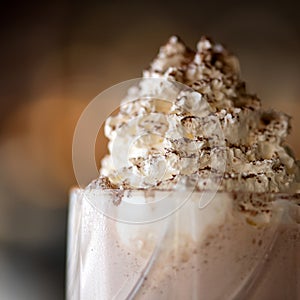 Airy foam on milkshake cocktail sprinkled with grated chocolate. Close up of Puffy whipped cream dessert or smoothie on