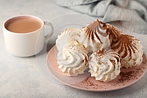 Airy vanilla zephyr on a pink plate, sprinkled with cocoa powder on top, a cup of fragrant cocoa