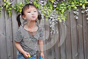 Aisa cute naughty lovely adorable child girl play with balloon kiss camera outdoor in summer park happy smile happiness childhood