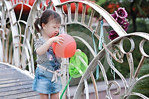 Aisa cute naughty lovely child girl play with balloon have fun outdoor in summer park happy smile happiness funny childhood