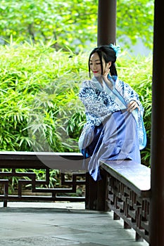 Aisan Chinese woman in traditional Blue and white Hanfu dress, kill time in a famous garden