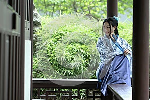 Aisan Chinese woman in traditional Blue and white Hanfu dress, kill time in a famous garden