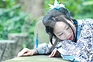 Aisan Chinese woman in traditional Blue and white Hanfu dress, kill time in a famous garden