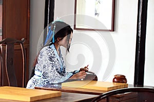 Aisan Chinese woman in traditional Blue and white Hanfu dress play the game of go