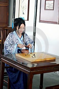 Aisan Chinese woman in traditional Blue and white Hanfu dress play the game of go