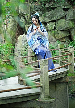 Aisan Chinese woman in traditional Blue and white Hanfu dress, play in a garden