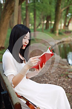 Aisan Chinese Young woman read book in nature outdoor park garden by lake sit on bench enjoy free lifestyle violin sunny day