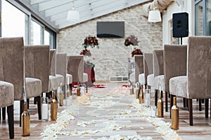 Aisle in the hall between brown chairs with white petals on the