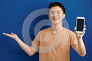 Aist-up shot happy enthusiastic man with bristle in purple t-shirt, stretch hand with smartphone showing gadget screen