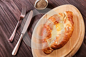 Ajarian Khachapuri traditional Georgian cheese pastry with eggs on cutting board.