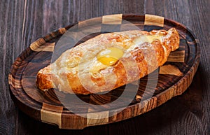 Ajarian Khachapuri traditional Georgian cheese pastry with eggs on cutting board.