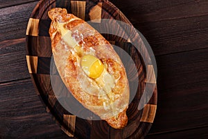 Ajarian Khachapuri traditional Georgian cheese pastry with eggs on cutting board. Homemade baking.