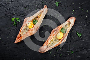 Ajarian Khachapuri traditional Georgian cheese pastry with eggs on dark wooden background