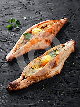 Ajarian Khachapuri traditional Georgian cheese pastry with eggs on dark wooden background