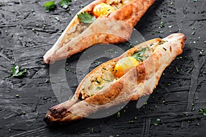 Ajarian Khachapuri traditional Georgian cheese pastry with eggs on dark wooden background.