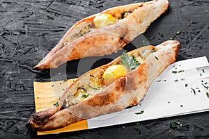 Ajarian Khachapuri traditional Georgian cheese pastry with eggs on dark wooden background.