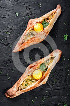 Ajarian Khachapuri traditional Georgian cheese pastry with eggs on dark wooden background