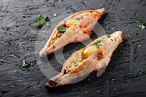 Ajarian Khachapuri traditional Georgian cheese pastry with eggs on dark wooden background.