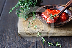 Ajvar pepper mousse or pindjur red vegetable spread made from paprika and tomatoes in wooden bowl on the rustic wooden table.