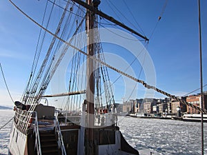 Aker Brygge in Oslo with a sailing ship lying in the Oslofjord  with ice floes, Norway