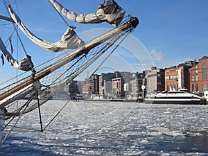 Aker Brygge in Oslo with a sailing ship lying in the Oslofjord  with ice floes, Norway