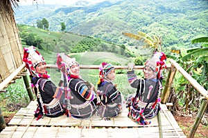 Akha hill tribe people sit and admire the view on Doi Mae Salong, Chiang Rai Province, Thailand.