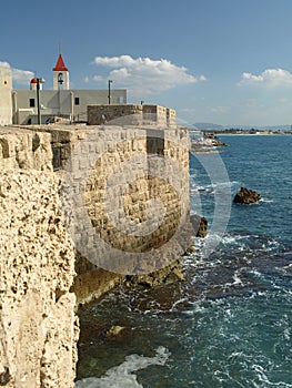 Akko Acre Sea Wall with church and sea defences on Akko Bay taken on a sunny day with blue sky and white fluffy clouds