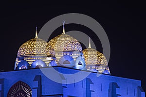 Al Ameen City Mosque glowing at night purple and yellow in Muscat, Oman